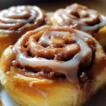 Homemade cinnamon buns fresh out of the oven, drizzled with icing.