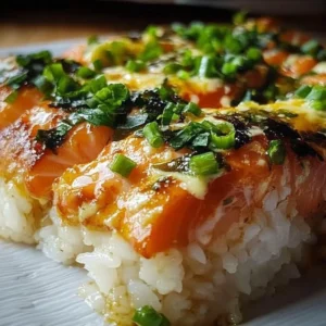 Baked spicy salmon sushi topped with scallions and sauce, a flavorful dish.