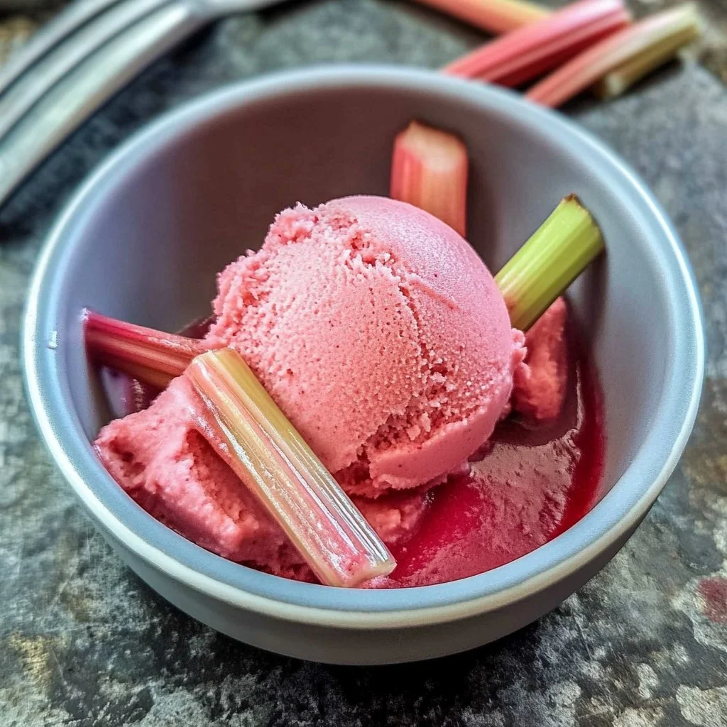 Delicious homemade rhubarb sorbet served in a bowl with fresh rhubarb stalks.