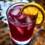 A refreshing glass of hibiscus lemonade with lemon slice and flower garnish