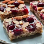 No-bake almond cherry dream bars topped with almonds and cherries
